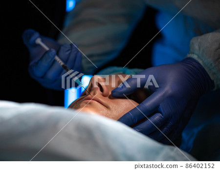 Doctor plastic surgeon makes an injection to resize the lips of a girl using fillers and hylauronic acid injections. Injection cosmtheology, close-up Doctor plastic surgeon makes an injection to resize the lips of a girl using fillers and hylauronic acid injections. Injection cosmtheology, close-up 86402152