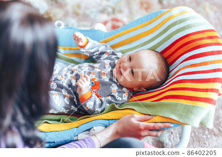 nice blue eyed Baby child relaxing on a sunbed or a deck chair colored bouncer at home 86402205