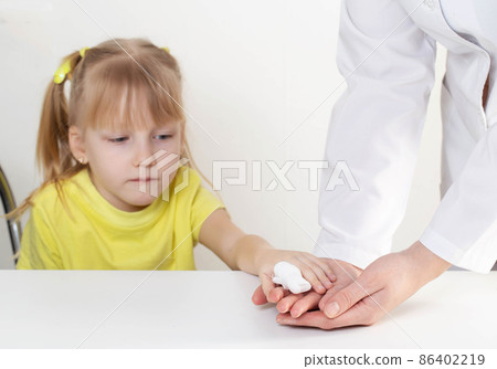 The doctor bandages the wound with a bandage, the child is a girl of 5 years, pediatric medicine The doctor bandages the wound with a bandage, the child is a girl of 5 years, pediatric medicine 86402219