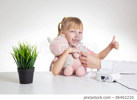 A 5-year-old caucasian girl is breathing into an inhaler at home. Treatment of cough and lung diseases in children, dilution of phlegm in the bronchi. A 5-year-old caucasian girl is breathing into an inhaler at home. Treatment of cough and lung diseases in children, dilution of phlegm in the bronchi. 86402220