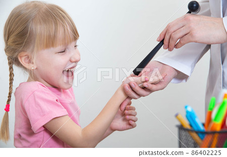 Doctor neuropathologist checks reflexes in the palm of a little caucasian girl 5 years old, neuropathology Doctor neuropathologist checks reflexes in the palm of a little caucasian girl 5 years old, neuropathology 86402225