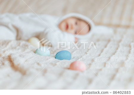 Cute smile happy little baby in white rabbit costume, playing with colorful easter eggs 86402883