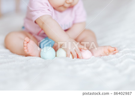 baby girl in pink clothes play with colour eggs on bed easter baby girl in pink clothes play with colour eggs on bed easter 86402987