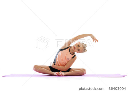 Portrait of sportive beautiful little girl, rhythmic gymnastics artist doing flexible exercises isolated on white studio background. Grace in motion, action. Portrait of sportive beautiful little girl, rhythmic gymnastics artist doing flexible exercises isolated on white studio background. Grace in motion, action. 86403004