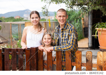Family of three posing at backyard garden 86403142