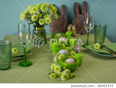 Set table with Easter decoration - eggs in nests and flowers. 86403143