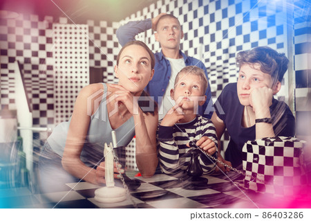 Thoughtful boys with parents solving conundrum in chess quest room Thoughtful boys with parents solving conundrum in chess quest room 86403286