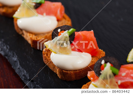 Toasted bread with creamy sauce, salmon and olives Toasted bread with creamy sauce, salmon and olives 86403442