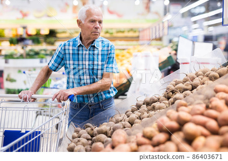 old age man choosing potato in supermarket 86403671