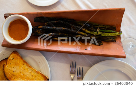 Calcots onions served on plate with Romesco sauce - traditional Catalan dish 86403840