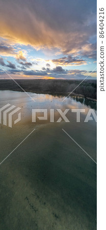 Beautiful, colorful sky over a lake at sunset. Peaceful scene, no one in sight.  86404216