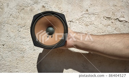 old worn speaker holden by a males hand in front of an vintage wall old worn speaker holden by a males hand in front of an vintage wall 86404527