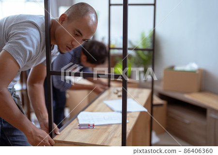 two male woodworker assembling new furniture together two male woodworker assembling new furniture together 86406360