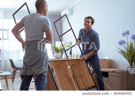 Two Male Movers Carrying a furniture and assmble it 86406405