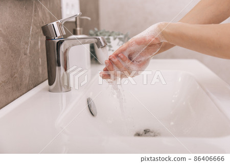 Washing hands under the flowing water tap. Washing hands rubbing with soap for corona virus prevention, hygiene to stop spreading corona virus in or public wash room. Hygiene concept hand detail. 86406666