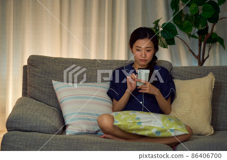 A woman looking at a smartphone at midnight 86406700