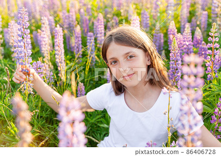 Happy teenage girl smiling outdoor. Beautiful young teen woman resting on summer field with blooming wild flowers green background. Free happy kid teenager girl, childhood concept Happy teenage girl smiling outdoor. Beautiful young teen woman resting on summer field with blooming wild flowers green background. Free happy kid teenager girl, childhood concept 86406728