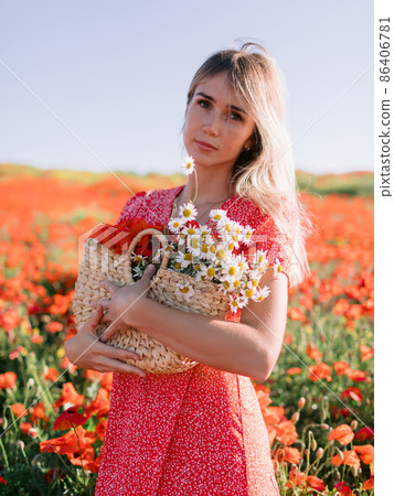 Caucasian blonde woman in a poppy field. Woman in red dress and handbag with wild flowers Caucasian blonde woman in a poppy field. Woman in red dress and handbag with wild flowers 86406781