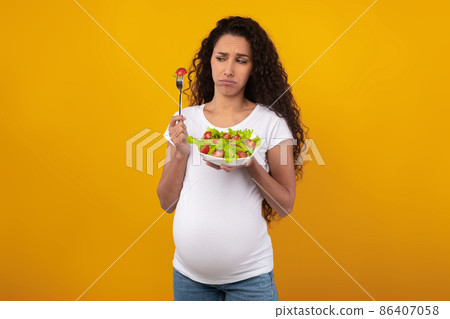 Portrait of Sad Pregnant Lady Holding Plate With Vegetable Salad 86407058