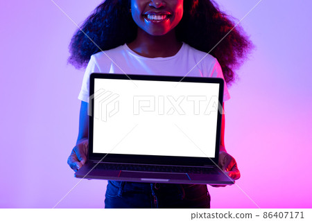 Unrecognizable young black woman holding laptop computer with empty screen in neon light, mockup for website design Unrecognizable young black woman holding laptop computer with empty screen in neon light, mockup for website design 86407171