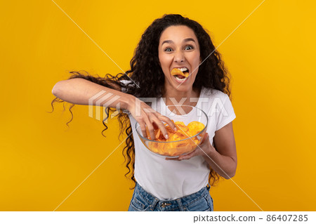 Excited Latin Lady Eating Delicious Potato Crisps Excited Latin Lady Eating Delicious Potato Crisps 86407285