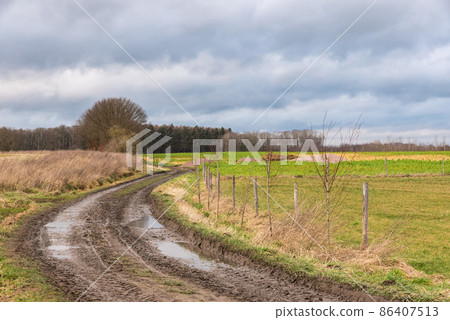 Mud path through the harvested fields at the Flemish countryside around Vertrijk, Belgium 86407513