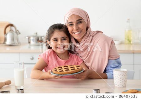 Baking Together. Portrait Of Happy Arabic Mother And Daughter Holding Homemade Pie Baking Together. Portrait Of Happy Arabic Mother And Daughter Holding Homemade Pie 86407535