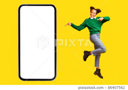 African Teenager Girl Pointing At Blank Phone Screen, Yellow Background 86407562