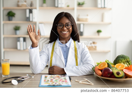 Portrait of happy african american nutritionist giving online consultations to patients, having video call in clinic 86407753