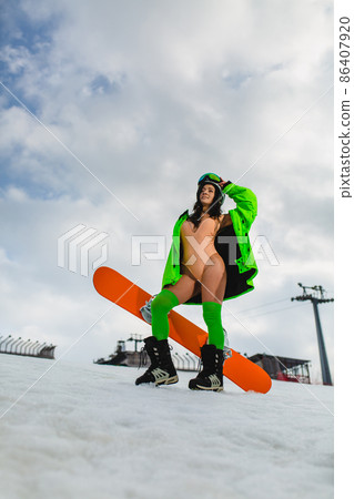 Young beautiful woman posing with a snowboard on a ski slope 86407920