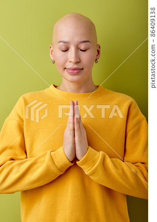 calm and gorgeous young bald woman with closed eyes posing at camera, praying. 86409138