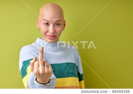 fuck off, beautiful bald woman wearing casual shirt standing over green background 86409166