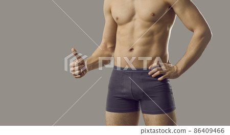 Attractive masculine young macho man in boxer underwear shows OK thumb up standing isolated on grey background. Shirtless handsome male with fit muscular body advertising viagra or impotence treatment 86409466