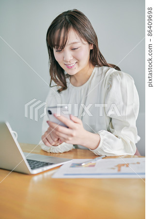 A young woman operating a smartphone during telework 86409698
