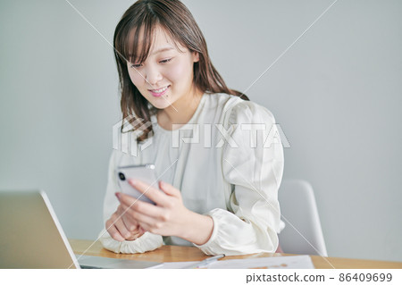 A young woman operating a smartphone during telework 86409699