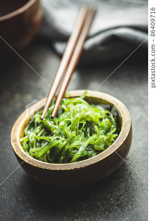 Green wakame. Seaweed salad in bowl on black table. 86409716