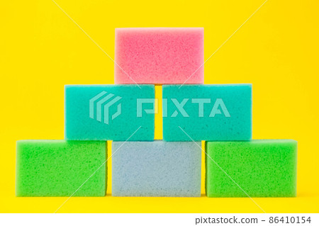 Multi-colored foam rubber sponge for cleaning and washing dishes on a yellow background. Top view, pattern Multi-colored foam rubber sponge for cleaning and washing dishes on a yellow background. Top view, pattern 86410154
