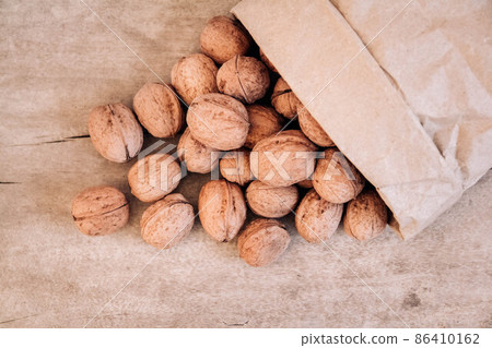 Walnuts in a paper bag on a old rustic table. Walnuts in a paper bag. Top view. Copy, empty space for text 86410162
