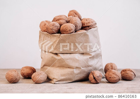 Walnuts in a paper bag on a old rustic table. Walnuts in a paper bag. Copy, empty space for text 86410163