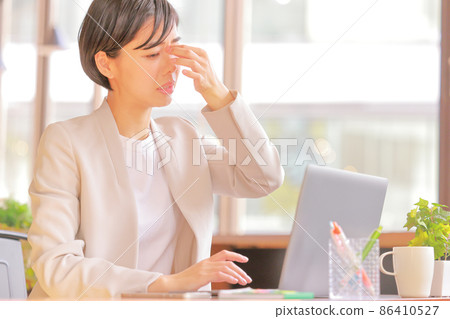 Eye fatigue_Business woman holding down temples 1 86410527