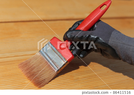 Painting or staining wooden terrace floor. Red brush, close-up. 86411516