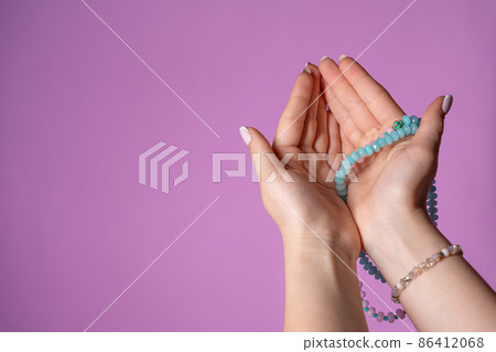 Woman holds in hand rosary or mala beads strand used for keeping count during mantra meditations Woman holds in hand rosary or mala beads strand used for keeping count during mantra meditations 86412068