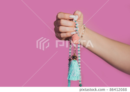 Woman lit hand counts mala beads strands of gemstones used for keeping count during mantra Woman lit hand counts mala beads strands of gemstones used for keeping count during mantra 86412088