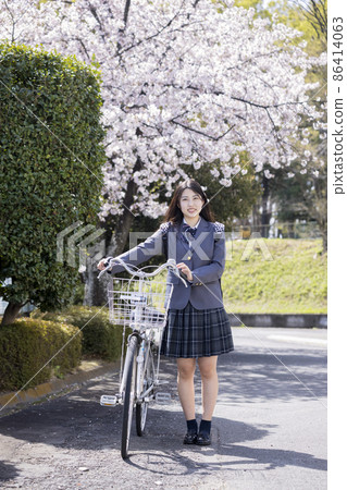 在櫻花中騎自行車上學的女高中生 86414063