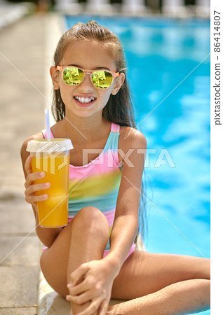 Girl with drink looking at camera near pool 86414807