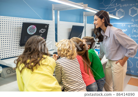 Teacher with children looking at screen at lesson Teacher with children looking at screen at lesson 86414890