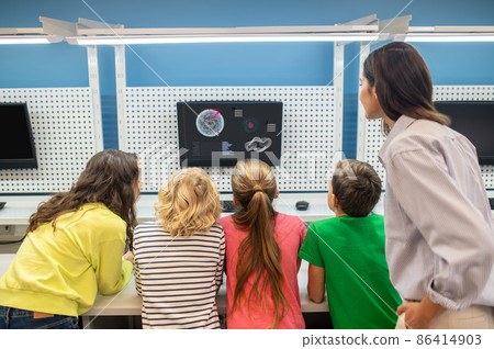 Back view of children and woman looking at screen Back view of children and woman looking at screen 86414903