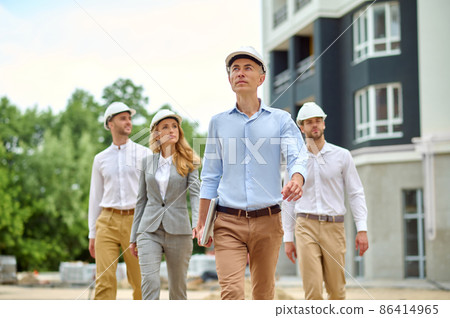 Group of four people walking across a new building site Group of four people walking across a new building site 86414965