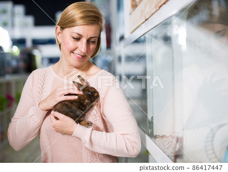 Portrait of woman looking for bunny in pet store Portrait of woman looking for bunny in pet store 86417447