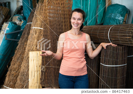 Young woman choosing organic wooden fence for gardening 86417463